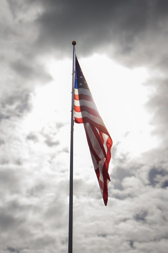The American flag waves against a cloudy sky, symbolizing freedom and patriotism.